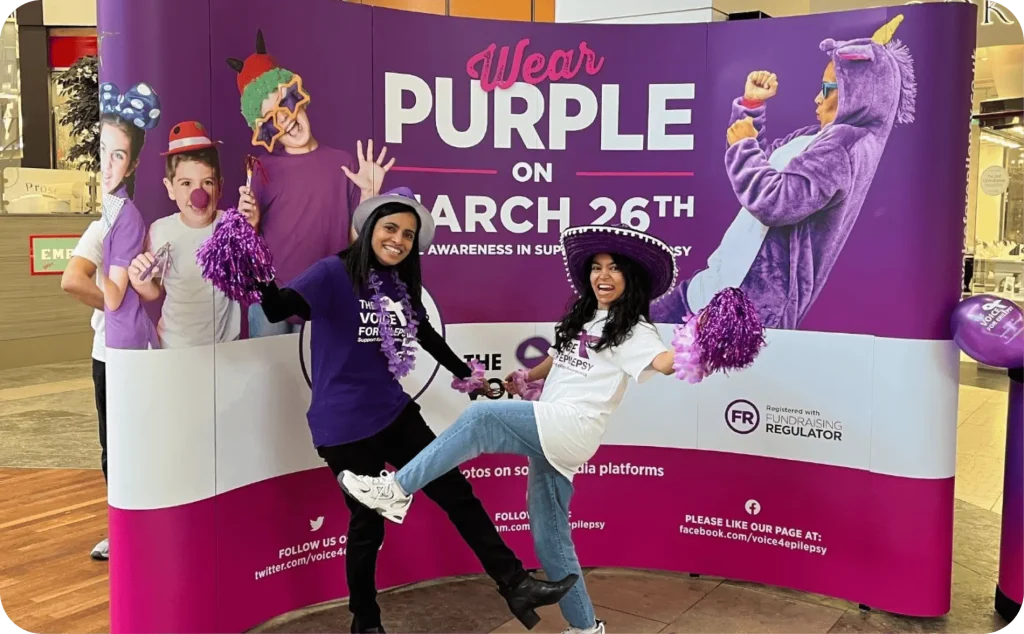 People celebrating Wear Purple on March 26th epilepsy awareness day with photo backdrop and mascot