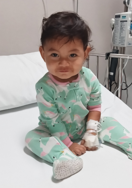 Young child Lia sitting on hospital bed during epilepsy treatment journey