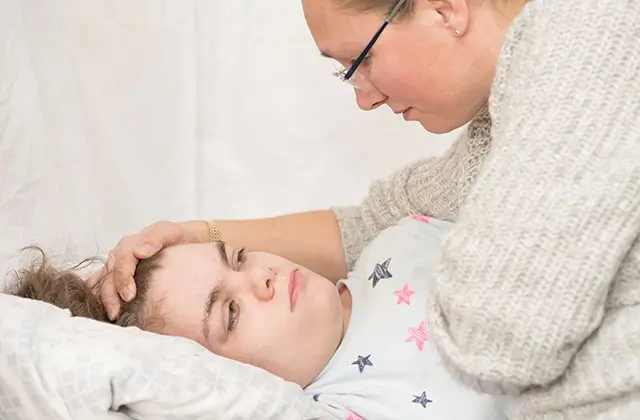 Mother caring for sick child in bed representing serious epilepsy concerns