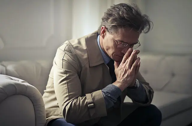 Person sitting on couch looking stressed representing emotional impact of epilepsy