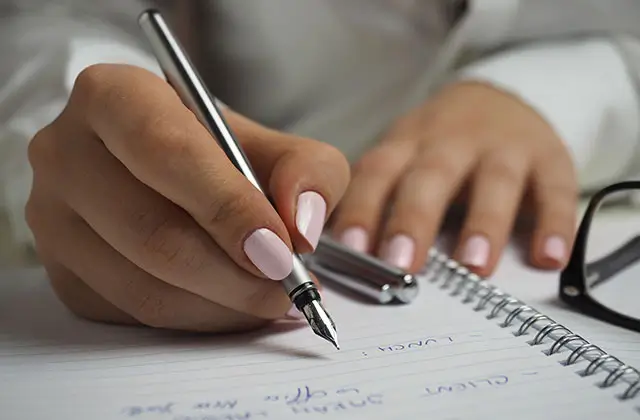 Person writing in notebook representing epilepsy management and tracking