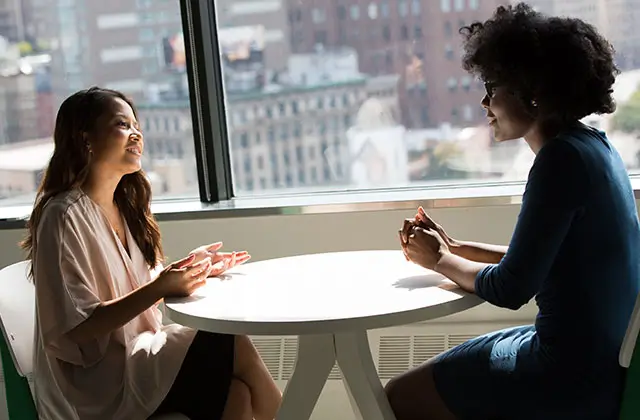 Two women having supportive conversation about epilepsy over coffee