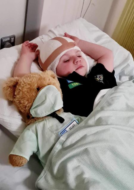Young child recovering in hospital bed after epilepsy seizure with monitoring equipment and IV treatment