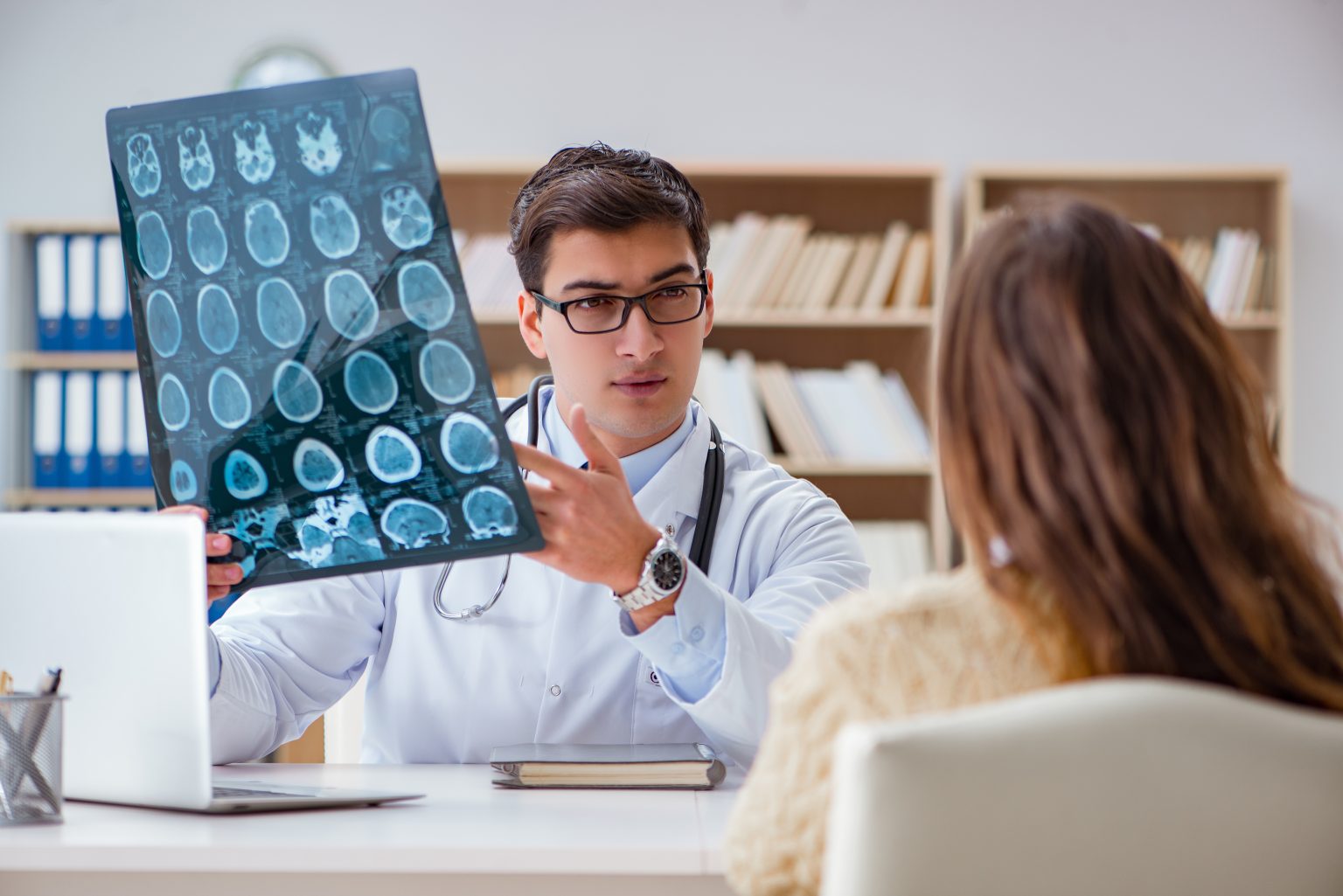 Neurologist doctor analyzing brain CT scan x-ray images for epilepsy diagnosis and treatment planning with patient