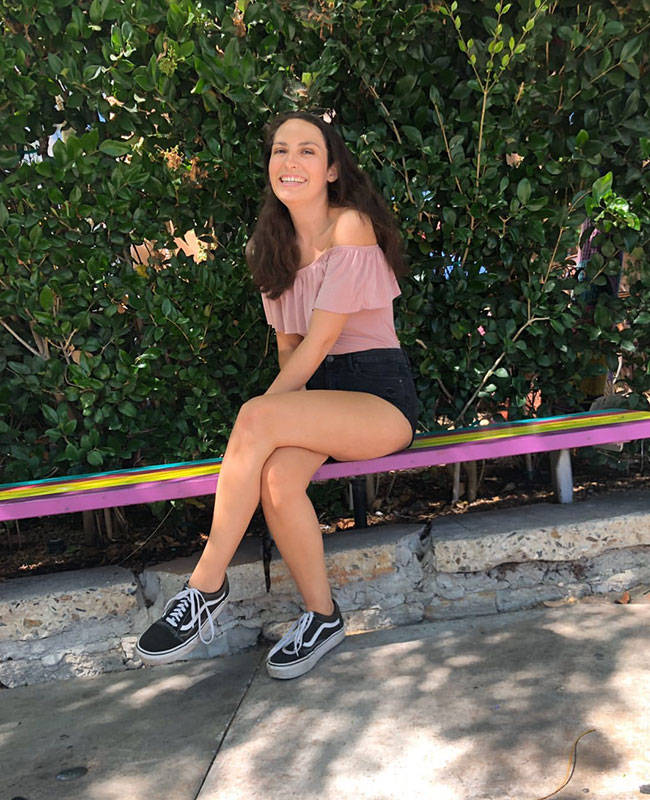 Addison Taylor sitting on colourful swing, casual lifestyle photo showing joy despite living with epilepsy