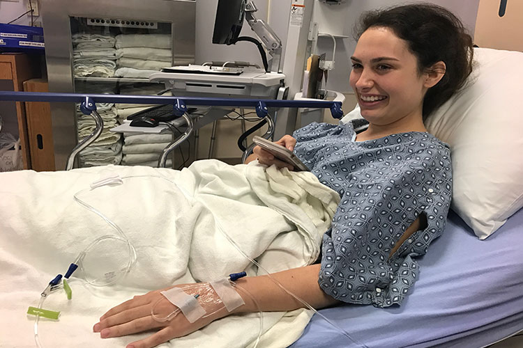 Addison Taylor smiling in hospital bed with IV during epilepsy treatment, maintaining positive spirits