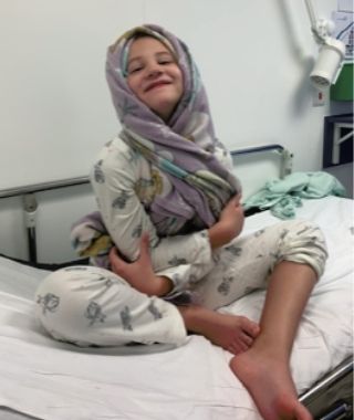 Young Harry smiling in hospital bed during epilepsy treatment, showing bravery and resilience