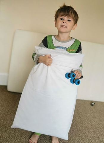 Young boy with epilepsy holding anti-suffocation safety pillow for nighttime seizure protection