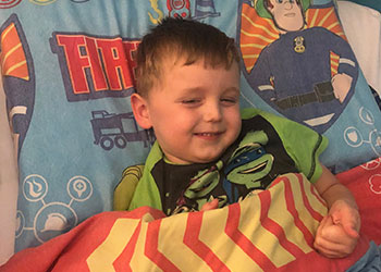 Happy young boy sleeping peacefully on anti-suffocation epilepsy safety pillow in bedroom